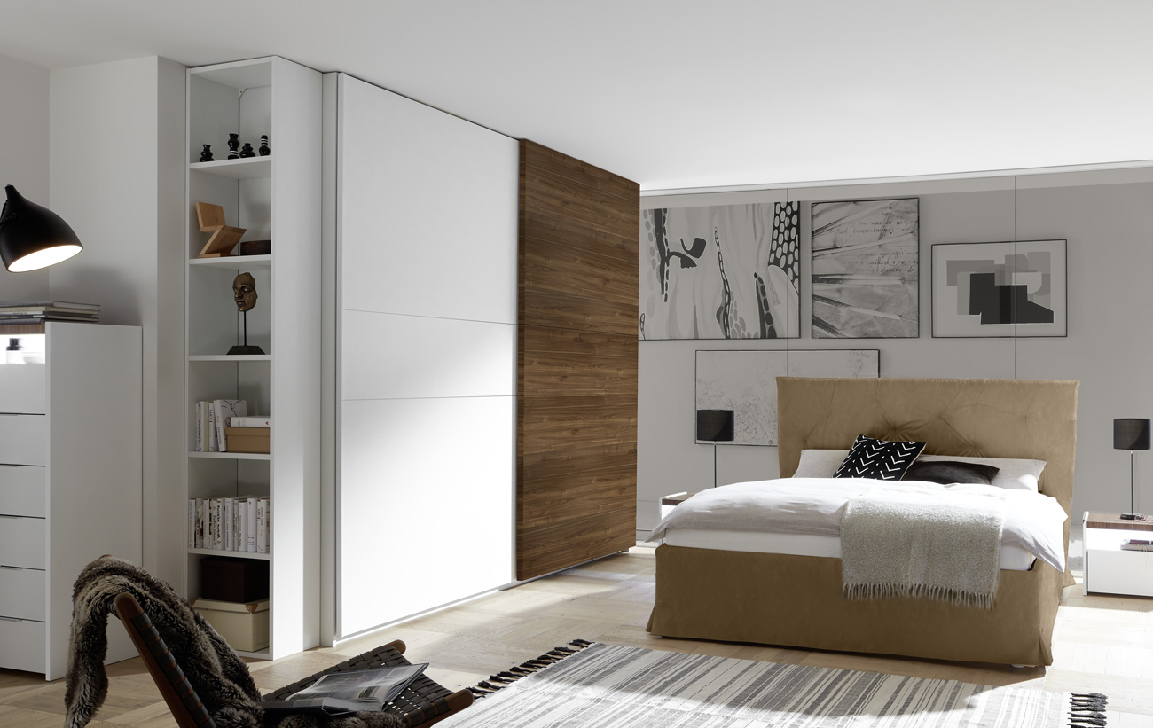 Camera matrimoniale con letto in ecopelle tabacco, armadio con anta noce dark e comodini bianchi opachi