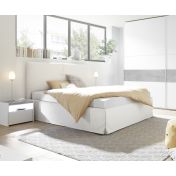 Camera matrimoniale con letto in ecopelle bianco, armadio con fascia beton e comodini bianchi opachi